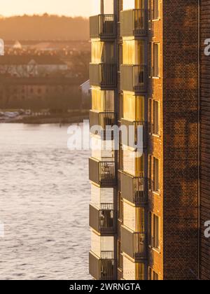 Die Seite eines Wohngebäudes in Göteborg strahlt mit dem warmen Licht der untergehenden Sonne und hebt die Balkone und Mauerwerk hervor. Die ruhige Rive Stockfoto