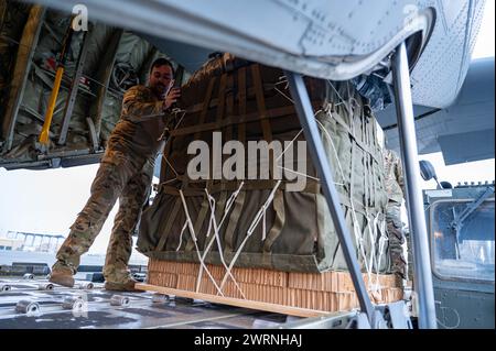 Zarqa, Jordanien. 11. März 2024. Ein Ladungsmeister der US-Luftwaffe platziert Paletten mit humanitärer Hilfe zum Verladen in die Frachtbucht eines C-130J Super Hercules-Flugzeugs der US-Luftwaffe auf der King Abdullah II Air Base am 11. März 2024 in Zarqa, Provinz Zarqa, Jordanien. Die Nahrungsmittelhilfe wird an palästinensische Flüchtlinge abgegeben, die vom israelischen Krieg gegen die Hamas gefangen sind. Foto: A1C Caleb Parker/US Air Force Photo/Alamy Live News Stockfoto