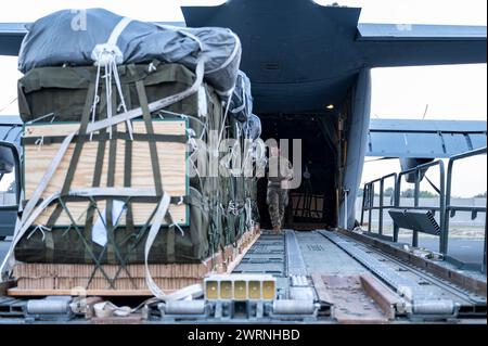 Zarqa, Jordanien. 11. März 2024. Ein Ladungsmeister der US-Luftwaffe platziert Paletten mit humanitärer Hilfe zum Verladen in die Frachtbucht eines C-130J Super Hercules-Flugzeugs der US-Luftwaffe auf der King Abdullah II Air Base am 11. März 2024 in Zarqa, Provinz Zarqa, Jordanien. Die Nahrungsmittelhilfe wird an palästinensische Flüchtlinge abgegeben, die vom israelischen Krieg gegen die Hamas gefangen sind. Foto: A1C Caleb Parker/US Air Force Photo/Alamy Live News Stockfoto