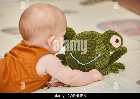 Das Baby spielt mit einem gestrickten Spielzeug im Kinderzimmer Stockfoto