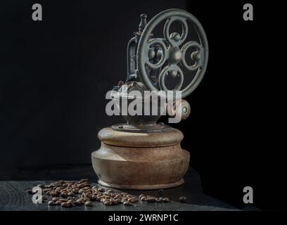 Alte originale Kaffeemühle mit Spuren von Zeit und Abrieb am Körper mit Kaffeebohnen auf dunklem Hintergrund. Antike Kaffeebohne Original META Stockfoto