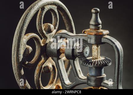 Nahaufnahme des originalen Rüttelrads aus Metall der antiken Kaffeebohne mit Handkurbel. Detail der alten Original Kaffeemühle auf dunklem Hintergrund, Kopiersack Stockfoto