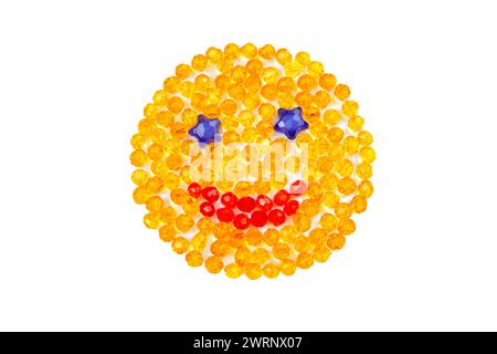 Lächelnder gelber Smiley mit Perlen auf weißem Hintergrund. Draufsicht. Stockfoto