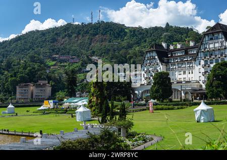 Teilweiser Blick auf den Quitandinha-Palast und die grünen Gärten des Platzes an der Quitandinha-Lagune unter dem sonnigen, bewölkten blauen Himmel am Sommernachmittag. Stockfoto