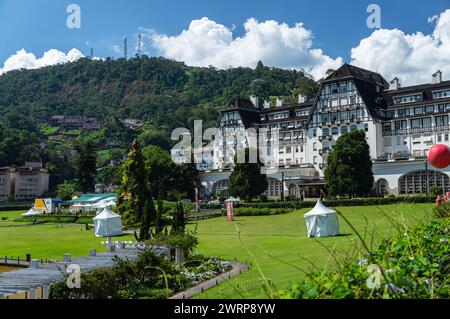 Teilweiser Blick auf den Quitandinha-Palast und die grünen Gärten des Platzes am Quitandinha-See unter dem sonnigen, wolkigen blauen Himmel am Sommernachmittag. Stockfoto