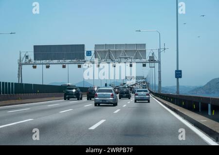 Starke Verkehrsbewegung über die Rio Niteroi-Brücke (Mario Covas Highway) bei KM 329-Markierung, während Sie unter dem blauen Himmel des Sommernachmittags in die Stadt Niteroi fahren. Stockfoto