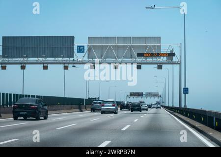 Starke Verkehrsbewegung über die Rio Niteroi-Brücke (Mario Covas Highway) bei KM 328-Markierung, während Sie unter dem blauen Himmel des Sommernachmittags in die Stadt Niteroi fahren. Stockfoto