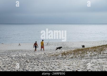 Menschen laufen in Richtung Atlantik am leeren Strand Praia Seca in der Nähe der Sao Judas Tadeu Straße unter dem bewölkten Sommernachmittagshimmel. Stockfoto