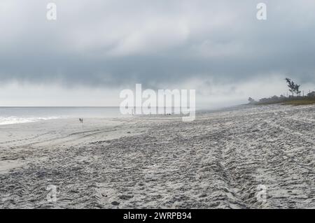 Westblick auf den breiten und friedlichen Praia Seca Strand, weiße Sandküste am Atlantischen Ozean im blauen Wasser unter dem wolkenblauen Himmel am Sommernachmittag. Stockfoto