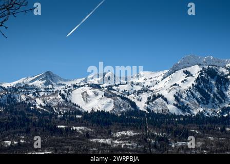 Ein Jetliner mit seinem Kondensstreifen über dem Skigebiet Snowbasin in der Nähe von Ogden, Utah. Das Foto stammt vom Wheeler Creek Trail. Stockfoto