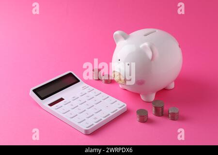 Finanzielle Einsparungen. Schweinebank, Münzen und Taschenrechner auf rosafarbenem Hintergrund Stockfoto
