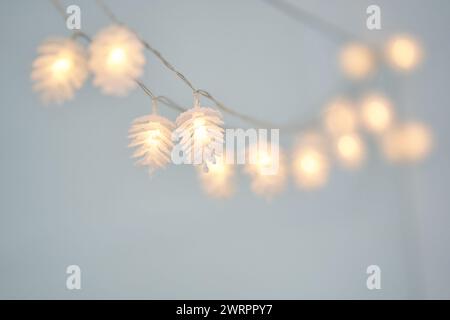 Nahaufnahme von Lichterketten in Form von Tannenzapfen mit Kopierraum. Weihnachtslichter, Dekorationshintergrund. Selektiver Fokus. Stockfoto