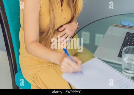 Schöne schwangere Frau, die am Laptop arbeitet. Eine junge Geschäftsfrau, die in ihrem Büro arbeitet Stockfoto