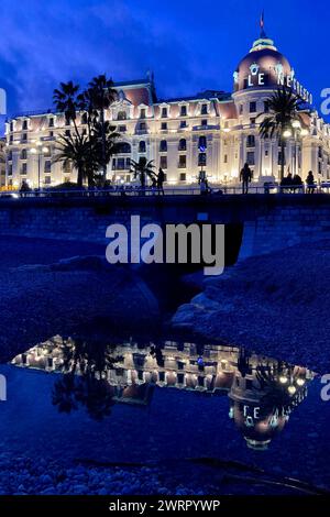 © Francois Glories/MAXPPP - 13/03/2024 Heure Bleu im Hotel Negresco, Promenade des Anglais, mit seiner Reflexion in einer Pfütze aus Meerwasser am Kiesstrand. Quelle: MAXPPP/Alamy Live News Stockfoto