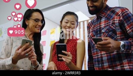 Symbole für digitale soziale Medien bewegen sich auf Smartphones über lächelndes Bürotrio. Stockfoto