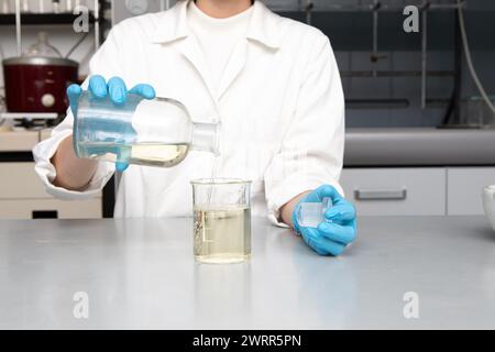 Gießen von Chemikalien für eine Analyse in einem Becher, das einen typischen Prozess in einem modernen wissenschaftlichen Labor darstellt Stockfoto