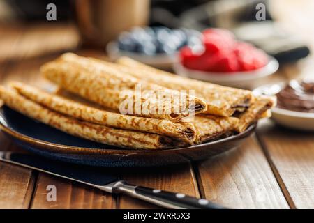 Frisch zubereitete goldene Crepes auf einem Teller, bereit zum Frühstück auf dem Tisch. Stockfoto