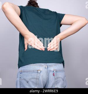 Das Bild fokussiert sich auf den unteren Rücken einer Person, da sie die typischen Schmerzen eines Bandscheibenvorfalls, einer häufigen Erkrankung der Wirbelsäule, erlebt Stockfoto