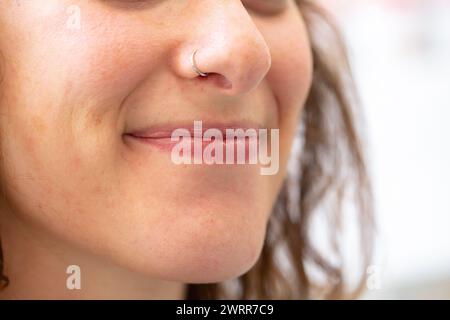 Ein Nahporträt einer fröhlichen Frau, die auf natürliche, entspannte Weise warm lächelt, ohne ihre Zähne zu enthüllen Stockfoto