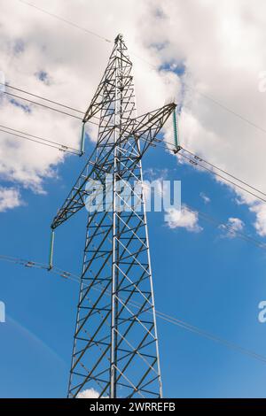 Ein Stromleitungsmast gegen Himmel und Wolken. Ansicht von unten Stockfoto