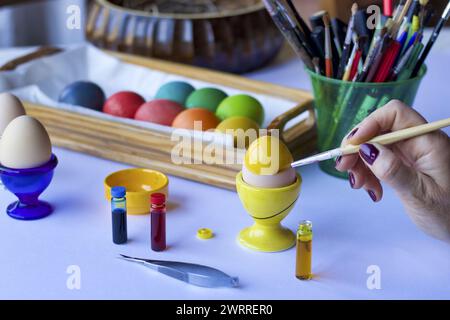 Frauenhandmalerei ostereier mit Lebensmittelfarben, Feiertagskonzept Stockfoto