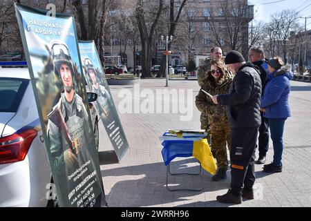 Die Bewohner sprechen mit Soldaten und Militärfrauen beim Rekrutierungspunkt der Nationalgarde der Ukraine in Zaporischschschi. Mit dem Beginn des dritten Kriegsjahres der Ukraine scheint der Sieg gegen Russland eine immer entferntere Perspektive zu sein. Die gescheiterte Gegenoffensive im vergangenen Sommer, kombiniert mit der verzögerten westlichen Hilfe, hat das ukrainische Militär in die Defensive gebracht. Die Notwendigkeit, erschöpfte Truppen aus den Kämpfen zu rotieren, stößt auf einen wachsenden Personalmangel. Die ukrainischen Streitkräfte brauchen mehr Kämpfer: Der Generalstab des Landes bat um 500.000 zusätzliche Männer, um die Al zu ergänzen Stockfoto