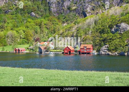 Typische rote Holzhäuser, Blockhütten entlang der Ufer des Fjords bei Brufjellhalene an der Küste des atlantischen Ozeans in Norwegen. Stockfoto