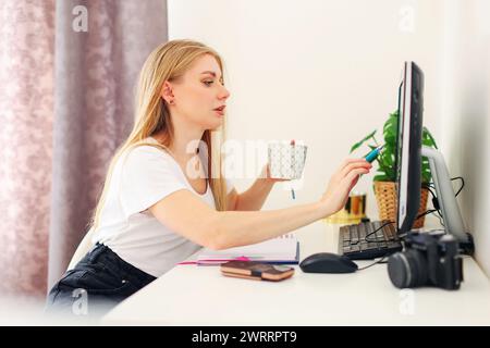 Die Schülerin bereitet sich auf Prüfungen vor und schreibt Informationen vom Computer in ein Notebook Stockfoto