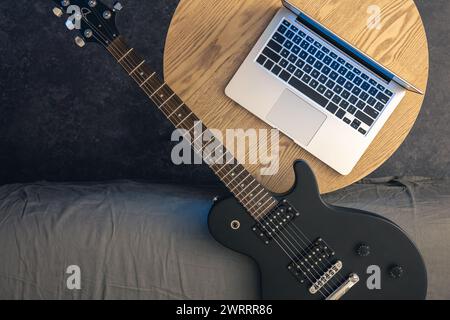 Elektrische Gitarre und Laptop auf einem Holztisch, Blick von oben. Stockfoto