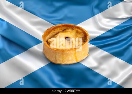 Das berühmte Backwarenprodukt eines Scotch Pie aus Schottland. Abgebildet auf einer schottischen Saltire-Flagge Stockfoto