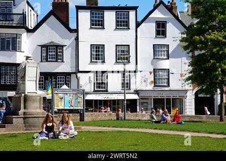 Traditionelle Gebäude in der Kathedrale in der Nähe mit einem Teil von Mols auf der linken Seite und Touristen genießen die Sonne, Exeter, Devon, Großbritannien, Europa. Stockfoto