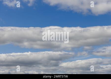 Himmel mit Schichten von Kumuluswolken, beleuchtet von einer sanften, hellblauen Ausstrahlung. Diese faszinierende Kulisse reicht bis zum Horizont Stockfoto