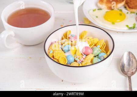 Osterfrühstück Müsli, Cornflakes mit Osterschokoladeneiern und Zuckerstreuseln, Milch oder Joghurt in Cornflakes Golden Breakfast Müsli Portion Stockfoto
