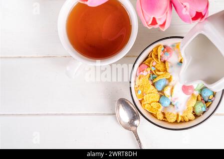Osterfrühstück Müsli, Cornflakes mit Osterschokoladeneiern und Zuckerstreuseln, Milch oder Joghurt in Cornflakes Golden Breakfast Müsli Portion Stockfoto