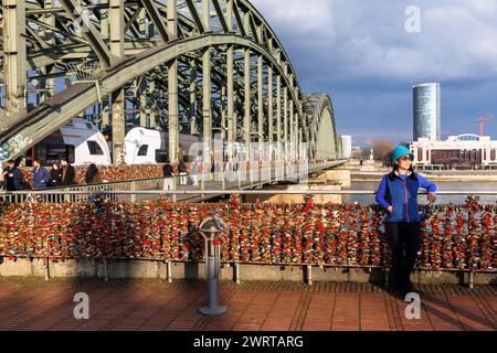 Love Schleusen an der Hohenzollernbrücke, Blick über den Rhein zum Wolkenkratzer KoelnDreieck und dem Hyatt Hotel im Deutz-Viertel, Touristen haben ihr Foto Stockfoto