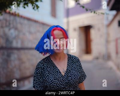 Weibliche Sommer-Altstadt Spaziergang in Antalya Türkei. Eine Frau mit bunten Haaren und Kleidern erkundet anmutig die historischen Straßen. Visuelle Sinfonie, die Vergangenheit und Gegenwart in Einklang bringt. Stockfoto