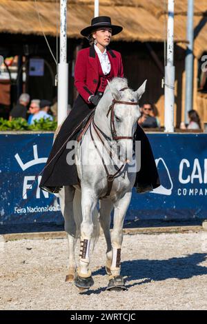 Portugal, Region Alentejo, Golega, Frau, die auf dem weißen Lusitano Pferd reitet und traditionelle Trachten trägt, auf der nationalen Pferdemesse von Golega Stockfoto