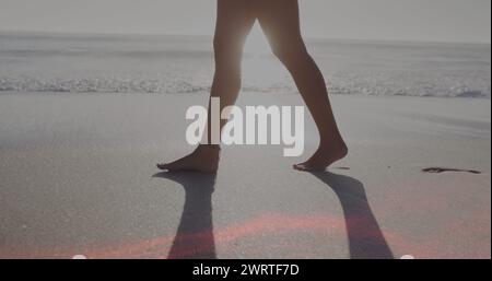 Bild von Lichtflecken über der kaukasischen Frau, die am Strand spaziert Stockfoto