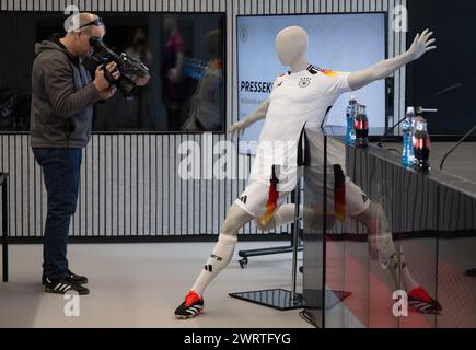 14. März 2024, Hessen, Frankfurt/Main: Ein Kameramann filmt vor Beginn der Pressekonferenz eine Schaufensterpuppe mit dem neuen offiziellen Europameistertrikot des DFB-Teams. Der deutsche Trainer Nagelsmann präsentiert die Mannschaft für die internationalen Testspiele Ende März auf einer Pressekonferenz am Nachmittag. Die DFB-Mannschaft spielt am 23. März in Lyon gegen Frankreich und am 26. März gegen die Niederlande in Frankfurt. Foto: Boris Roessler/dpa Stockfoto