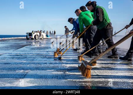 240215-N-DF558-1042 PAZIFISCHER OZEAN (15. Februar 2024) Seeleute schrubben das Flugdeck des Flugzeugträgers USS Abraham Lincoln (CVN 72) der Nimitz-Klasse Stockfoto