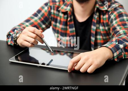 Mann mit Tablet und Stift auf weißem und schwarzem Hintergrund. Leerer leerer Bildschirm. Nahaufnahme. Stockfoto