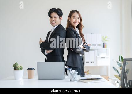 Geschäftsleute, die im Büro mit dem Rücken zueinander stehen, nachdem sie darüber gesprochen haben, wie man ein Unternehmen in einem modernen Arbeitsbereich gemeinsam führen kann, die beiden. Stockfoto