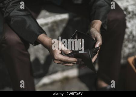 Mitarbeiter, die aus dem Unternehmen entlassen oder zurückgetreten sind, öffnen ihre Geldbörsen, um Münzen zu sehen. Arbeitslos, Einstellung, Kündigung des Arbeitsplatzes Konzept. Stockfoto