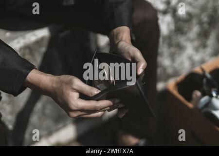 Mitarbeiter, die aus dem Unternehmen entlassen oder zurückgetreten sind, öffnen ihre Geldbörsen, um Münzen zu sehen. Arbeitslos, Einstellung, Kündigung des Arbeitsplatzes Konzept. Stockfoto