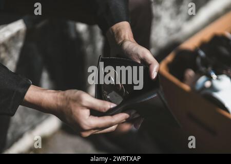 Mitarbeiter, die aus dem Unternehmen entlassen oder zurückgetreten sind, öffnen ihre Geldbörsen, um Münzen zu sehen. Arbeitslos, Einstellung, Kündigung des Arbeitsplatzes Konzept. Stockfoto