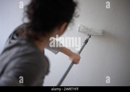 Berlin, Deutschland. Februar 2024. Eine Frau malt eine Wand in einem Zimmer weiß. Quelle: Sebastian Gollnow/dpa/Alamy Live News Stockfoto