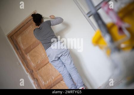 Berlin, Deutschland. Februar 2024. Eine Frau klebt eine Tür in einem Raum, bevor sie malt. Quelle: Sebastian Gollnow/dpa/Alamy Live News Stockfoto