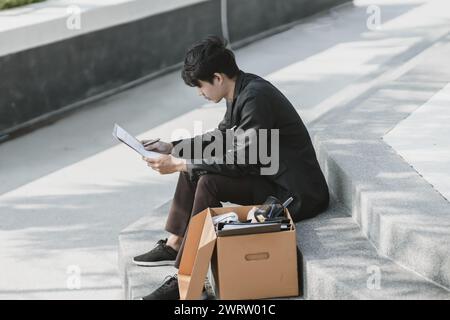 Mitarbeiter, die aus dem Unternehmen entlassen wurden oder aus dem Unternehmen entlassen wurden, schreiben ein Bewerbungsformular. Arbeitslos, Einstellung, Kündigung des Arbeitsplatzes Konzept. Stockfoto