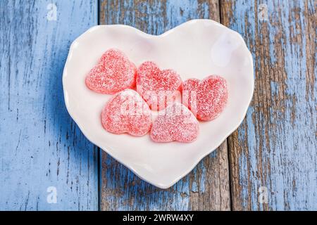 Herzförmige Gelee-Bonbons auf weißem herzförmigem Teller Stockfoto