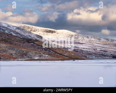 Der gefrorene Llyn Ogwen Lake Wales mit schneebedeckten Bergen im Hintergrund Stockfoto